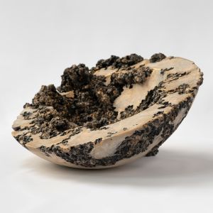 Photograph of a sculpted clay hemisphere form with irregular organic matter emerging from form