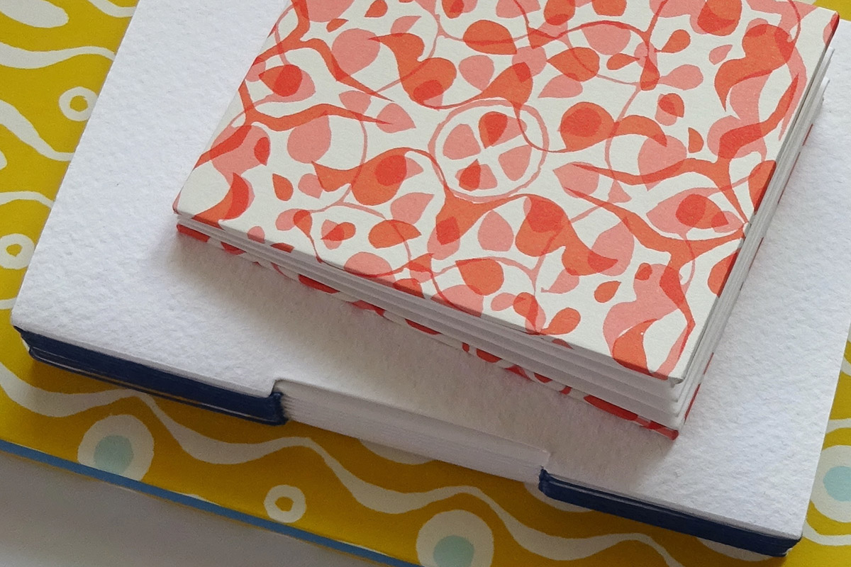 Pile of colourful buttonhole binding and pocket fold accordion books made by bookbinding tutor Megan Stallworthy