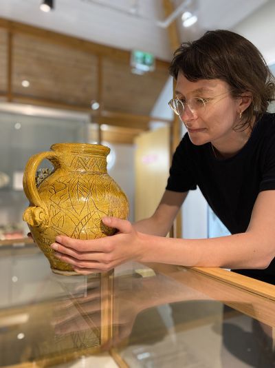 Florence Dwyer examines a ceramic jug with sgraffito decoration